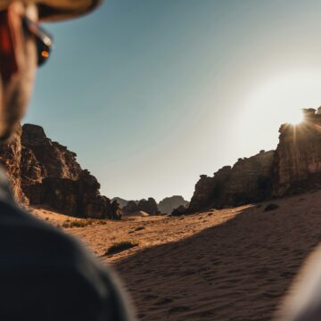 a man standing in the desert looking at the sun