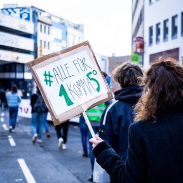 woman in blue jacket holding brown and green sign