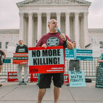 a man holding a sign that says no more killing