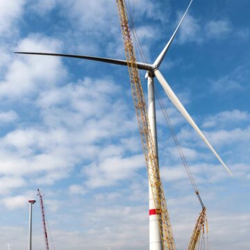 a large wind turbine sitting on top of a lush green field