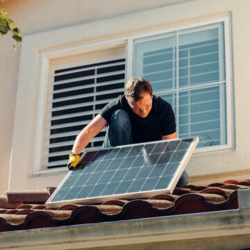 Man in Black Shirt Sitting on Brown Roof