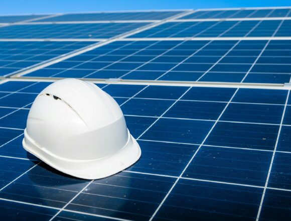 Photo by Evgeniy Alyoshin a white hard hat sitting on top of a solar panel