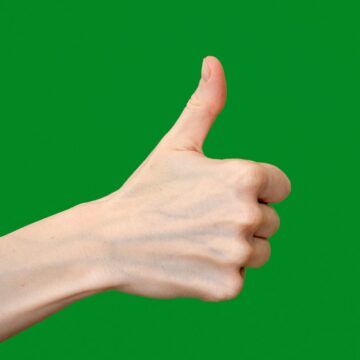 a hand giving a thumbs up sign against a green background