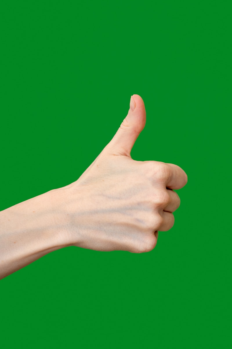 Photo by Anastasiya Badun a hand giving a thumbs up sign against a green background